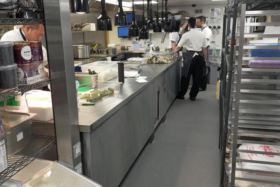 Commercial kitchen preparation area at Noci in Battersea during service, showing a chef working at a long stainless steel counter